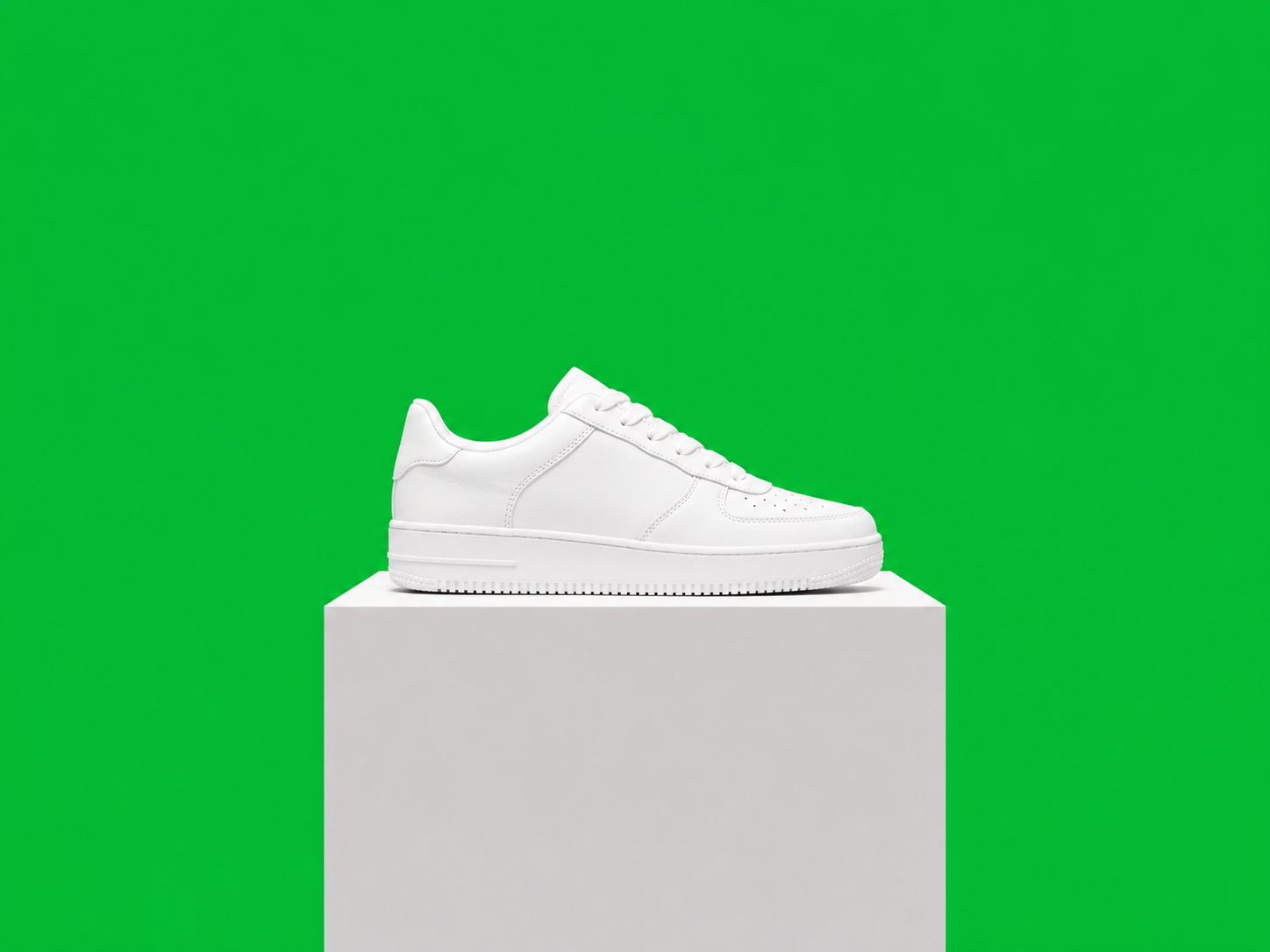 White sneaker on a pedestal against a vivid chroma-green screen before background removal
