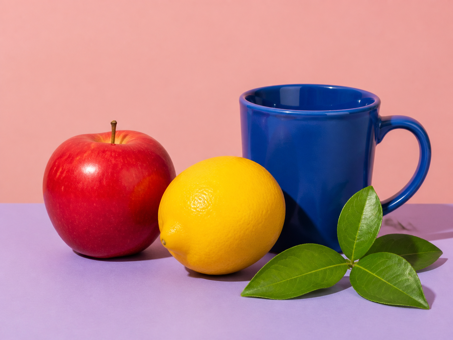 Colorful still life with an apple, lemon, blue mug, and leaves